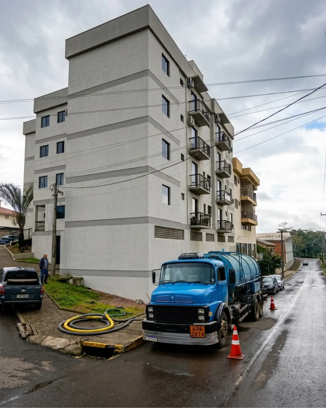 Caminhão auto vácuo com mangueiras conectadas diante de prédio residencial